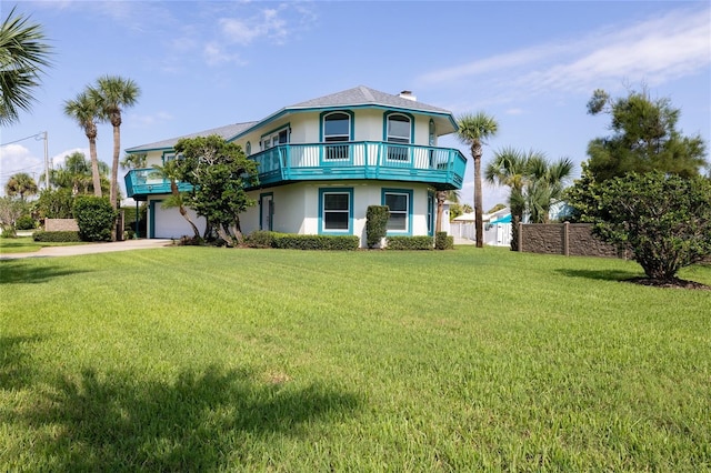 view of front of house featuring driveway, a front lawn, a balcony, and stucco siding