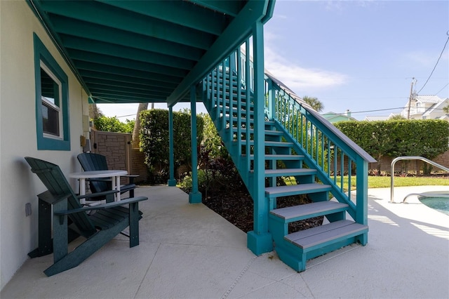 view of patio featuring stairs and fence