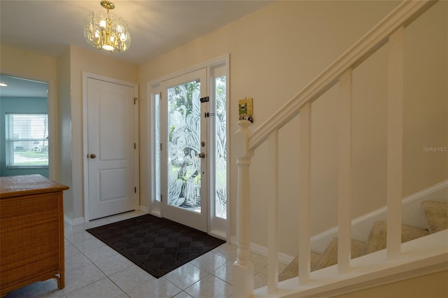 foyer entrance with stairs, light tile patterned flooring, and an inviting chandelier