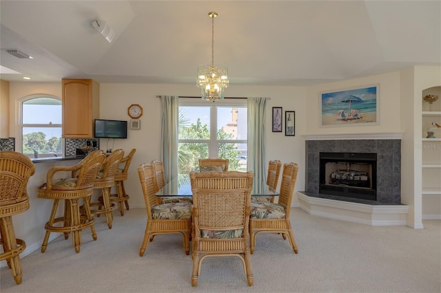 dining space featuring visible vents, a fireplace with raised hearth, light colored carpet, lofted ceiling, and a notable chandelier