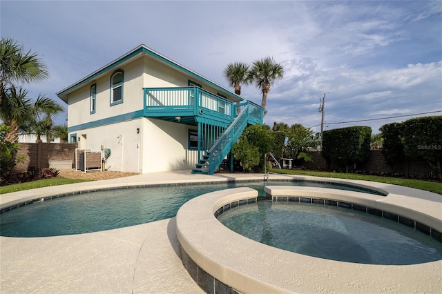 view of pool with stairs, fence, a deck, a patio area, and a pool with connected hot tub