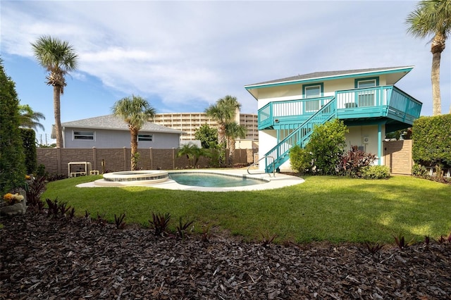 rear view of house featuring stairs, an in ground hot tub, a fenced backyard, and stucco siding