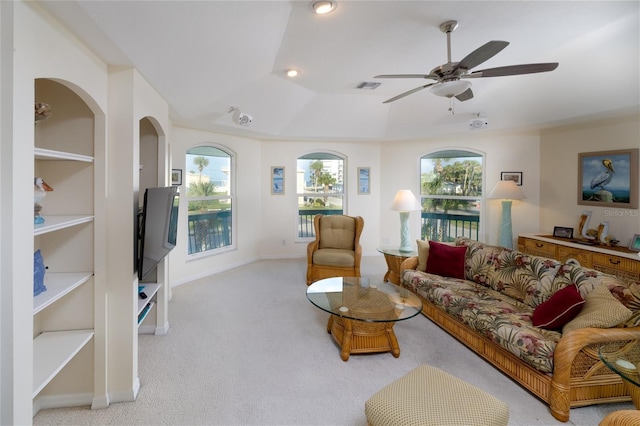 living room featuring baseboards, a ceiling fan, visible vents, and light colored carpet