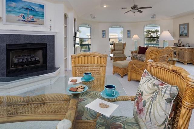 living room featuring ceiling fan, built in features, and a tiled fireplace