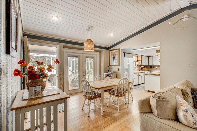 dining area with vaulted ceiling, crown molding, french doors, and light hardwood / wood-style floors