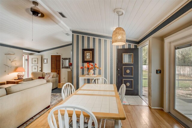 dining space featuring light hardwood / wood-style floors, ornamental molding, and lofted ceiling