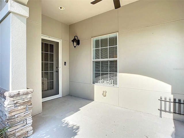 entrance to property featuring a patio area, a ceiling fan, and stucco siding