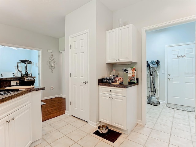 kitchen featuring light tile patterned floors, baseboards, and white cabinets