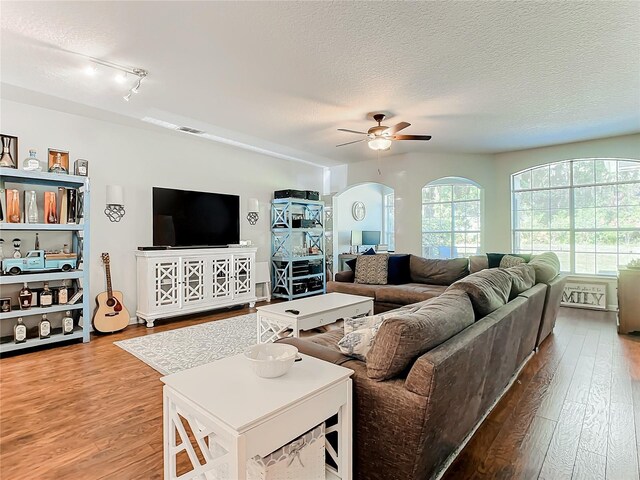 living room featuring light wood-type flooring, a textured ceiling, and ceiling fan