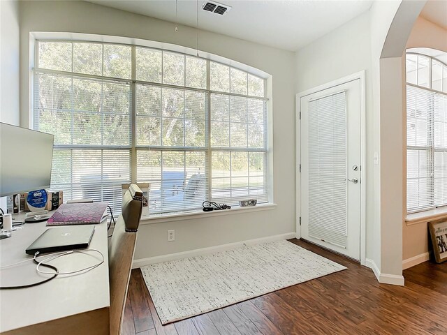 home office featuring plenty of natural light and dark hardwood / wood-style flooring