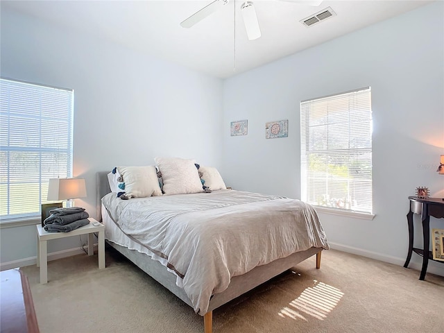 bedroom featuring a ceiling fan, visible vents, light carpet, and baseboards