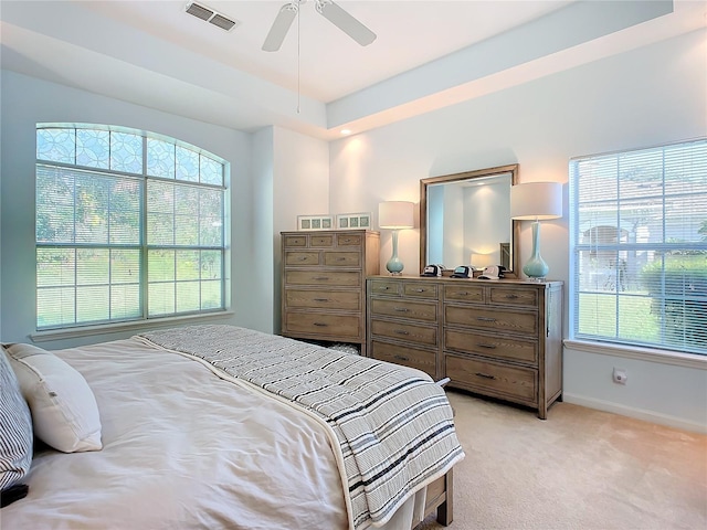 bedroom featuring light carpet, baseboards, multiple windows, and visible vents