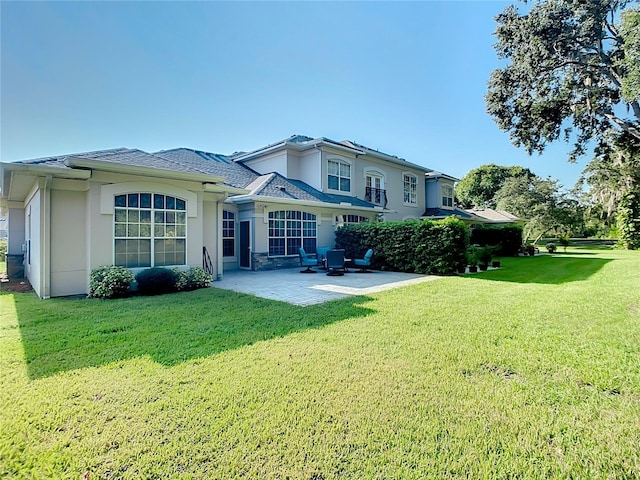 rear view of house featuring a lawn, a patio area, and stucco siding