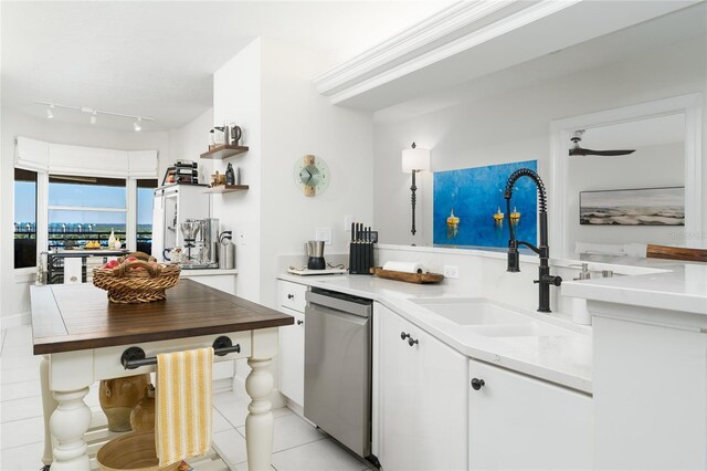 kitchen with a sink, dishwasher, light tile patterned floors, and white cabinetry