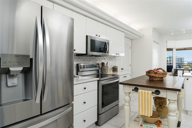 kitchen with butcher block countertops, backsplash, stainless steel appliances, white cabinets, and light tile patterned floors