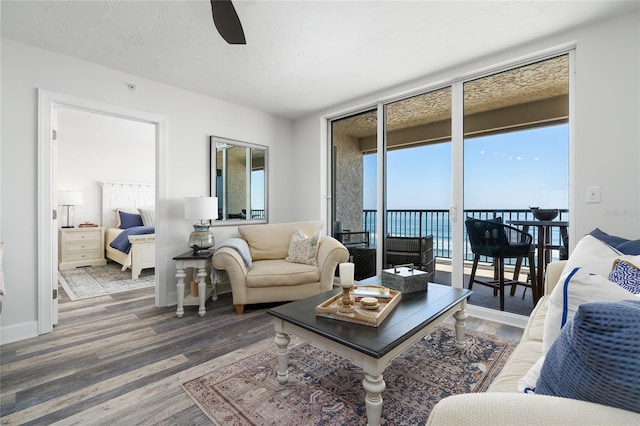 living area with plenty of natural light, wood finished floors, and a ceiling fan