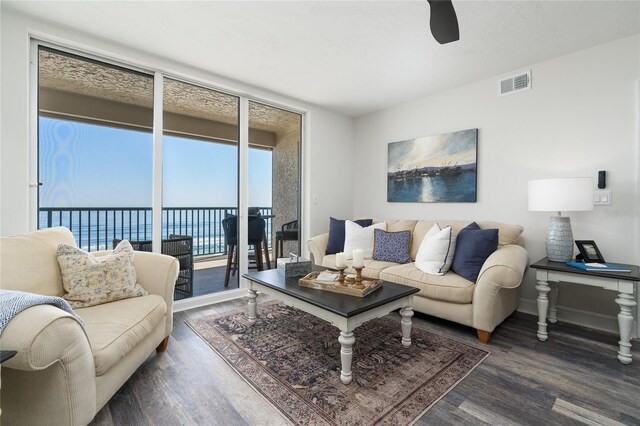 living room with visible vents, a water view, wood finished floors, floor to ceiling windows, and baseboards