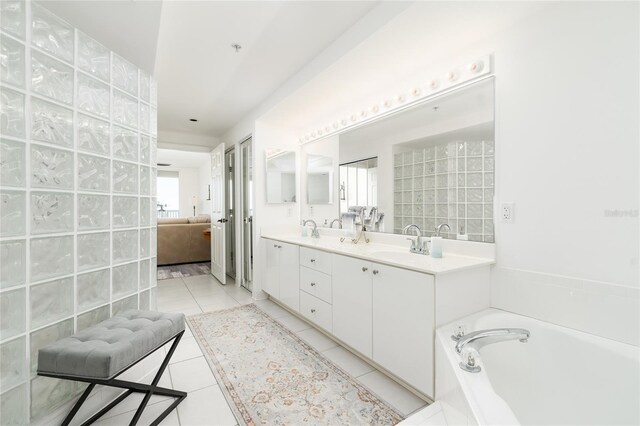 full bath featuring tile patterned floors, a garden tub, double vanity, and a sink