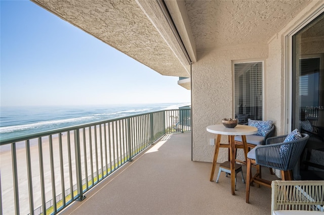 balcony featuring a view of the beach and a water view