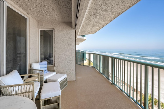 balcony with a water view and a view of the beach