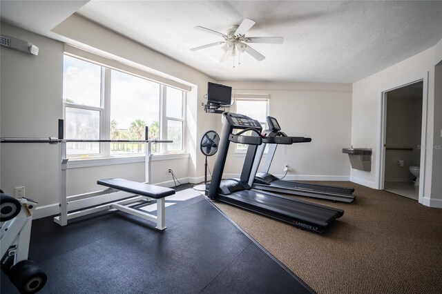 workout area featuring a ceiling fan and baseboards