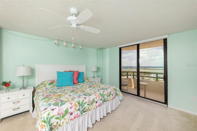 carpeted bedroom featuring baseboards, ceiling fan, access to outside, a textured ceiling, and floor to ceiling windows