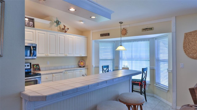 kitchen featuring appliances with stainless steel finishes, white cabinets, tile countertops, light tile patterned floors, and lofted ceiling