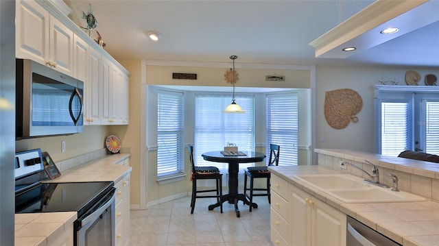 kitchen with stainless steel appliances, white cabinetry, sink, tile counters, and light tile patterned flooring