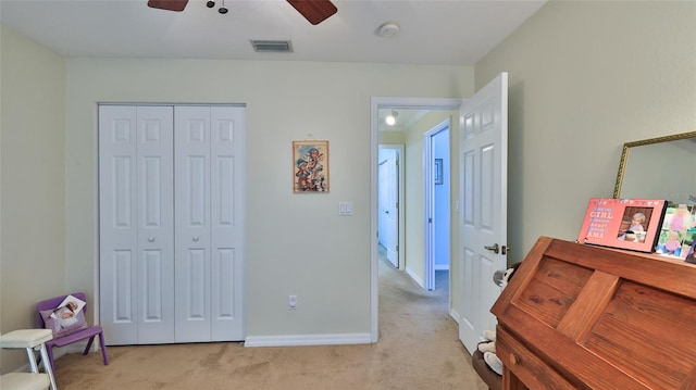 bedroom with a closet, ceiling fan, and light carpet