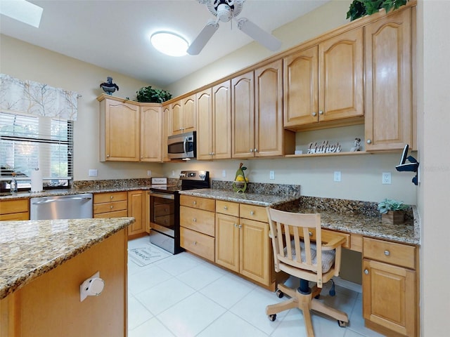 kitchen featuring a skylight, built in desk, light tile patterned floors, stone countertops, and stainless steel appliances