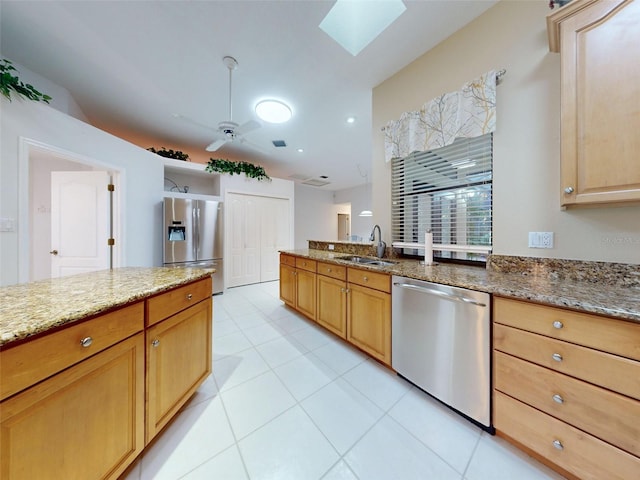 kitchen featuring sink, a skylight, ceiling fan, appliances with stainless steel finishes, and stone countertops