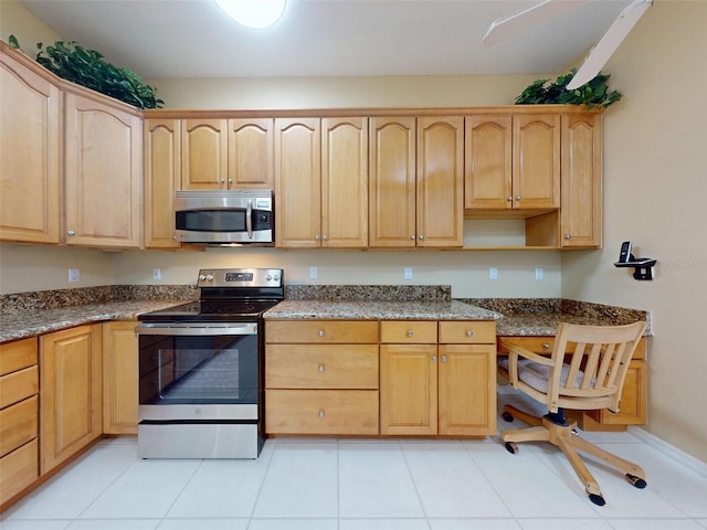 kitchen featuring light tile patterned floors, dark stone counters, and appliances with stainless steel finishes