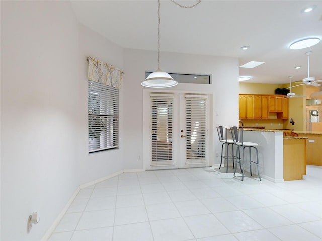 kitchen with french doors, a kitchen breakfast bar, hanging light fixtures, ceiling fan, and kitchen peninsula