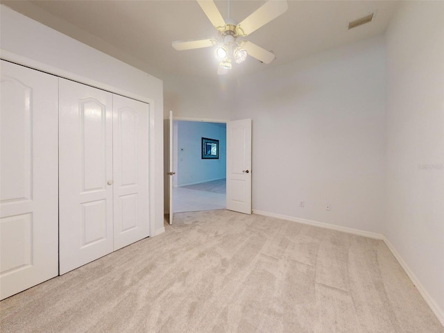 unfurnished bedroom with ceiling fan, light carpet, and a closet