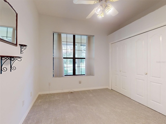 unfurnished bedroom featuring ceiling fan, a closet, and light carpet