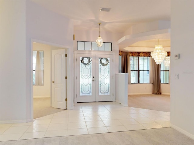 foyer featuring a notable chandelier, light carpet, and french doors