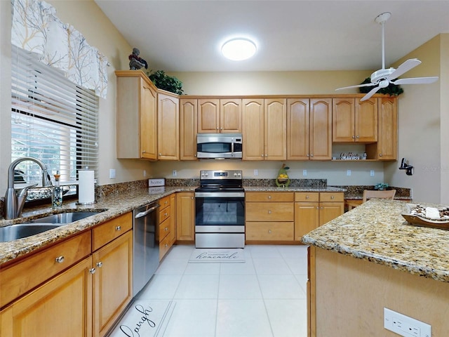 kitchen featuring light stone countertops, stainless steel appliances, ceiling fan, sink, and light tile patterned floors