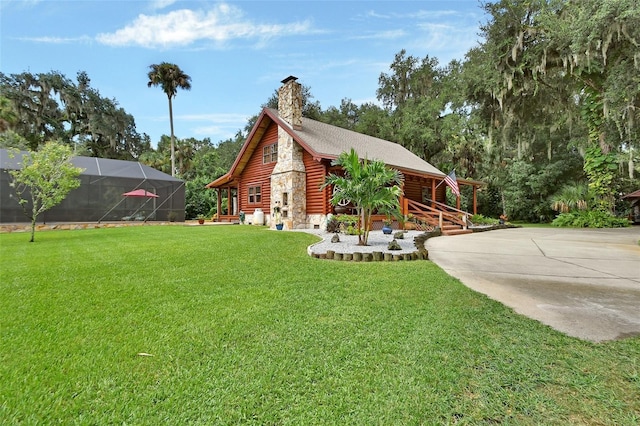 view of front of property featuring concrete driveway, log exterior, glass enclosure, a chimney, and a front yard