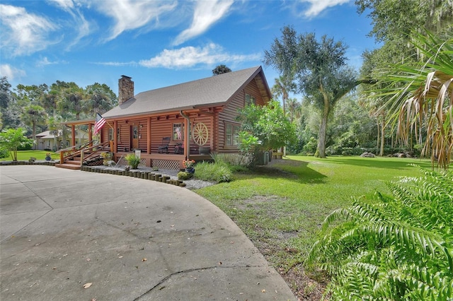 view of property exterior with covered porch, a lawn, a chimney, and log siding