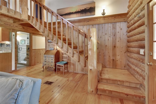 staircase featuring wood-type flooring, visible vents, and log walls