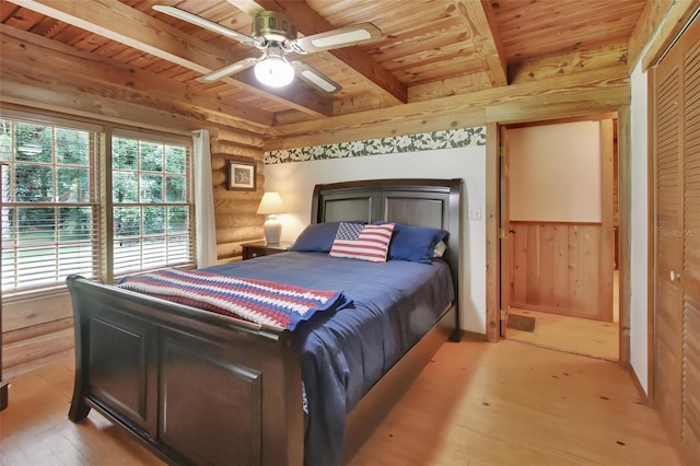 bedroom with beam ceiling, log walls, a ceiling fan, light wood-type flooring, and wooden ceiling