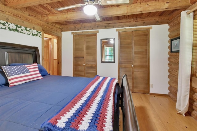 bedroom featuring wood finished floors, wood ceiling, multiple closets, beam ceiling, and rustic walls