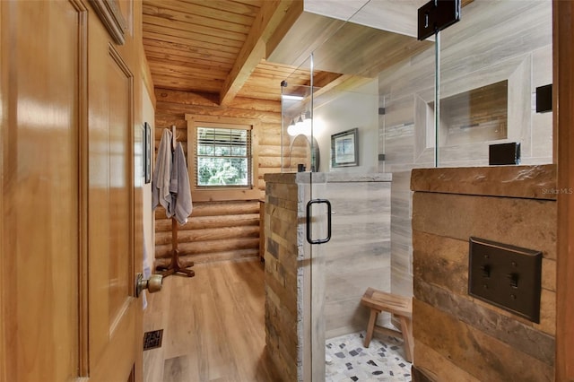 full bathroom featuring wooden ceiling, wood finished floors, a shower stall, beam ceiling, and rustic walls