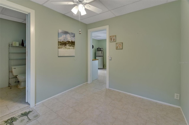 empty room with a paneled ceiling, baseboards, and a ceiling fan