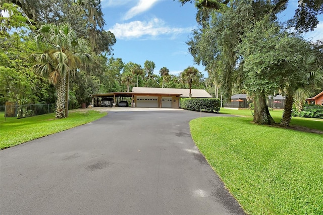 ranch-style home featuring driveway, a front lawn, and a detached garage