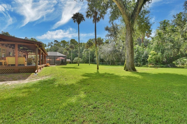 view of yard featuring glass enclosure and a deck