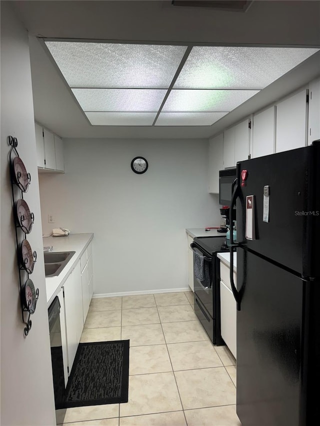 kitchen featuring light tile patterned flooring, sink, a paneled ceiling, white cabinetry, and black appliances