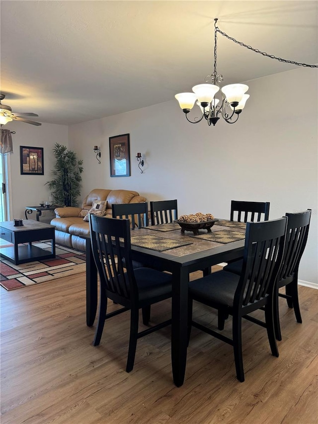 dining space with light wood-type flooring and ceiling fan with notable chandelier