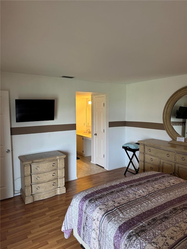 bedroom with hardwood / wood-style flooring and ensuite bath