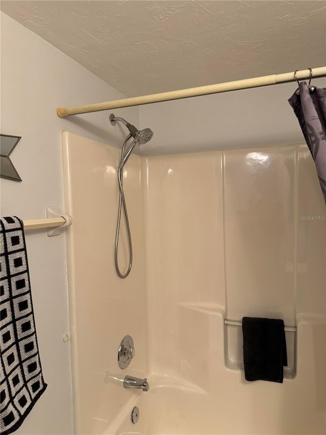 bathroom with shower / bath combination with curtain and a textured ceiling